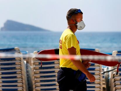 Un socorrista camina con máscara por la playa de Levante de Benidorm (Alicante), cerrada al público.