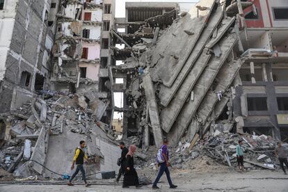 Un grupo de personas caminan entra la destrucción de edificios en Gaza, este viernes.