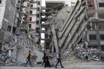 Un grupo de personas caminan entra la destrucción de edificios en Gaza, este viernes. 