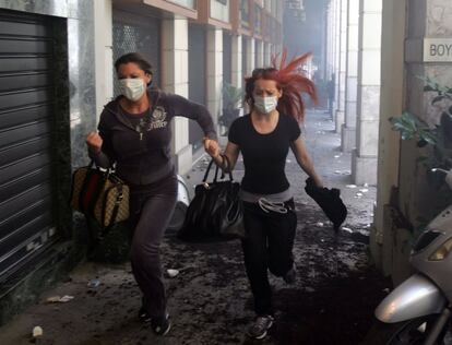Dos manifestantes corren por una galería en Atenas.