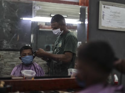 Um barbeiro da favela de Mandela, no Rio de Janeiro, trabalha com máscara de proteção durante pandemia de coronavírus.