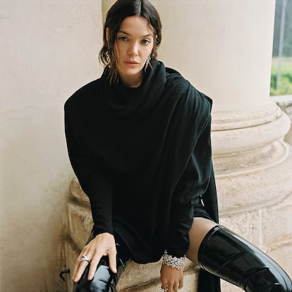 Vestido de punto, botas altas y medias, todo de SAINT LAURENT. Joyas de la colección de alta joyería Mediterranea de BVLGARI: pendientes en oro blanco con 2 diamantes pera, 30 rubíes pera y redondos, 2 diamantes redondos talla brillante, 18 diamantes marquesa, 30 diamantes talla fantasía, 14 diamantes talla brillante redondos y pavé de diamantes, anillos en platino con rubíes y diamantes y pulsera en platino con 5 diamantes talla esmeralda, un diamante talla asscher, 9 diamantes ovalados, 8 diamantes talla brillante redondo y pavé de diamantes.