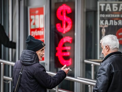 Russian men speak to each other in front of a panel displaying the Euro and Dollar signs at an exchange office in Moscow, Russia, 09 February 2023.