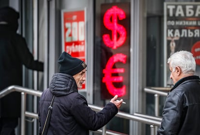 Russian men speak to each other in front of a panel displaying the Euro and Dollar signs at an exchange office in Moscow, Russia, 09 February 2023.