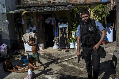 Un oficial armado de la Unidad de Policía Pacificadora patrulla por la favela de Providencia, en Río, junto a unos niños que están jugando. Sólo entre enero y abril de este año, una ola de violencia causó la muerte de 40 personas en Río, entre ellos el niño de 10 años Eduardo de Jesús Ferreira, a quien un policía disparó en la cabeza sin que se conozcan los motivos cuando se encontraba sentado en la puerta de su casa en el Complexo do Alemão, una favela del norte de Río.