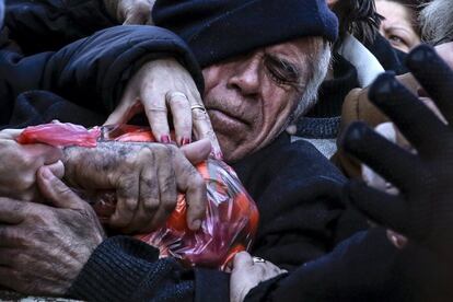 Un home aferra una bossa de mandarines lliurades pels agricultors durant una protesta per la proposta del govern de reformar el sistema de pensions del país, a Atenes (Grècia), el 27 de gener del 2016.