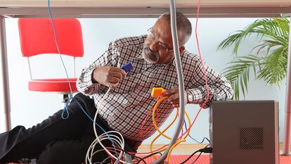 Un hombre debajo de la mesa protegiendo los cables