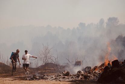 Vecinos intentan apagar el fuego con mangueras, barrio Bufalvent en Manresa, este lunes.