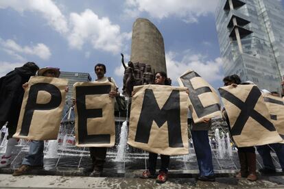 Cinco personas en la capital de México sostienen carteles con las siglas de Petróleos Mexicanos (Pemex).