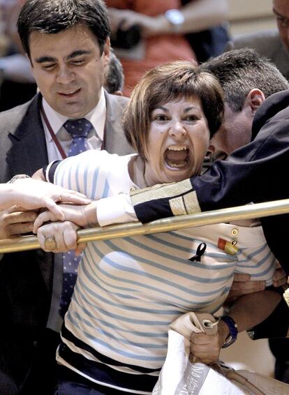 Un ujier intenta sacar de la tribuna de invitados del Senado a una de las esposas de los mineros tras la protesta.