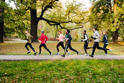 Un grupo de corredores hace deporte alrededor de un parque.