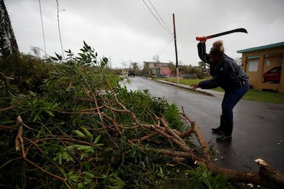 Una mujer corta trozos de un árbol caído por el paso del huracán en Guayama, Puerto Rico. María dejó una devastación "extensa" cuando atravesó la isla, según el gobernador de la isla, Ricardo Roselló.