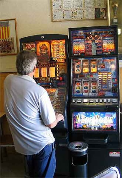 Un hombre juega en una máquina tragaperras en un bar.