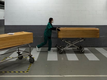 A worker at a funeral home moving the coffin of a coronavirus victim.