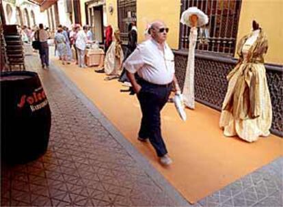 Un hombre pasa frente a un puesto ropa del mercadillo solidario, en la calle Francos.