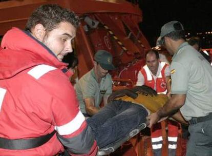 Miembros de la Guardia Civil y de la Cruz Roja atienden a uno de los 35 inmigrantes subsaharianos (11 mujeres y 24 hombres que han llegado esta madrugada al puerto de Motril en Granada