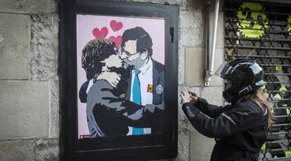 Una intervencion artistica de TVBoy en una calle contigua al Palau de la Generalitat, muestra como Rajoy y Puigdemont se dan un beso en la boca.