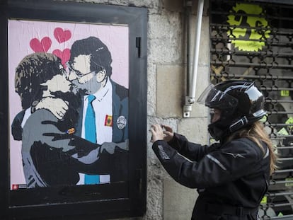 Una intervencion artistica de TVBoy en una calle contigua al Palau de la Generalitat, muestra como Rajoy y Puigdemont se dan un beso en la boca.