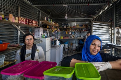 Duas mulheres servem comida em um pequeno restaurante que montaram no campo de refugiados de Ritsona.