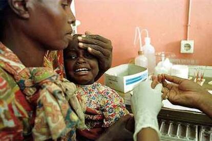 Una mujer sostiene a su hija, enferma de malaria, en el hospital mozambiqueño de Manhiça.