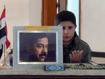 Un niño iraquí reza  junto al retrato de Sadam Husein en Tikrit, en el aniversario de la ejecución del dictador.