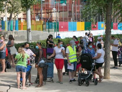 Decenas de vecinos hacen cola en el barrio de Aluche para recoger una bolsa con alimentos este sábado.