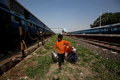 Siddharth Dhage, de 10 años, transporta contenedores de agua vacíos a lo largo de las vías del tren en la estación de tren de Aurangabad, India.