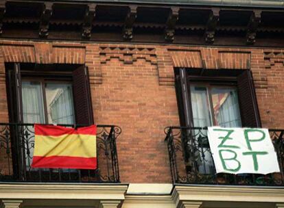 La bandera nacional junto a un mensaje contra el presidente del Gobierno en unos balcones de Madrid.