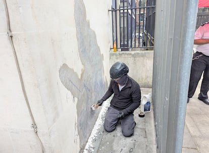 Un trabajador elimina este miércoles el mural de Banksy, que mostraba a un juez golpeando a un manifestante, en el exterior del Tribunal Superior de Justicia de Londres.