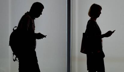 Dos personas usando sus teléfonos móviles.