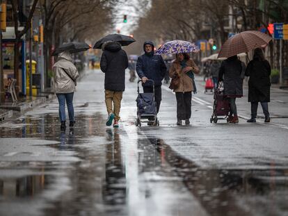 Varias personas pasean por una calle de Barcelona un día de lluvia.
