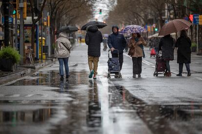 Varias personas pasean por una calle de Barcelona un día de lluvia.