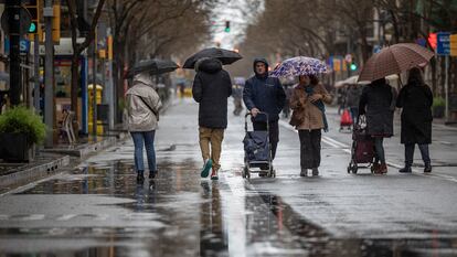 Varias personas pasean por una calle de Barcelona un día de lluvia.