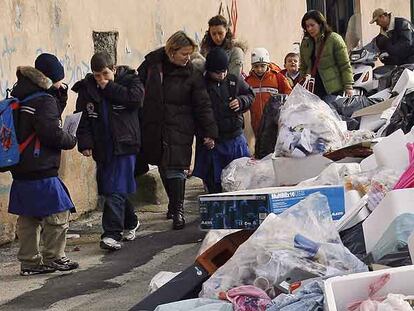 Niños que van al colegio con sus madres pasan junto a montañas de basura ayer en un barrio de Nápoles.