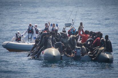Marineros del 'Avallone' se acercan a la patera para dar instrucciones a los migrantes a bordo antes del rescate. Mientras, ellos muestran uno de los niños a bordo.