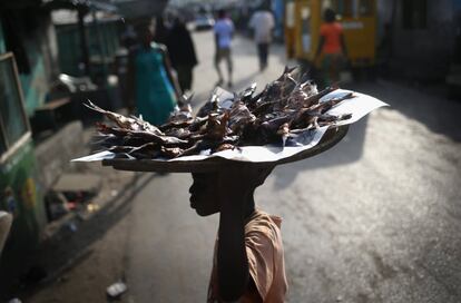 Un niño lleva, sobre su cabeza, pescado frito en un mercado de Monrovia, donde la actividad vuelve a parecerse a la que había antes del brote de ébola.