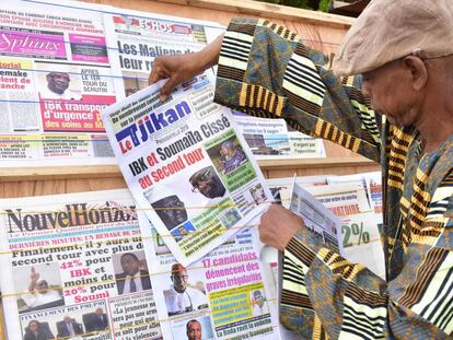 Un hombre mira un periódico en las calles de Bamako, en el que aparecen en primera página los dos contendientes.