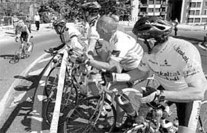 Un grupo de cicloturistas anima a una de las participantes del Tour femenino en las calles de Bilbao.