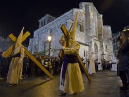 Dos cofrades de la Penitente Hermandad de Jesús Yacente de Zamora cargan con su cruz durante la procesión que recorre las calles de Zamora en la noche de Jueves Santo. EFE/Archivo