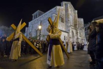 Dos cofrades de la Penitente Hermandad de Jesús Yacente de Zamora cargan con su cruz durante la procesión que recorre las calles de Zamora en la noche de Jueves Santo. EFE/Archivo