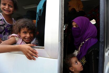 Una mujer iraquí y sus hijos suben al autobús que les llevará desde el campo de Dibaga de vuelta a su aldea.