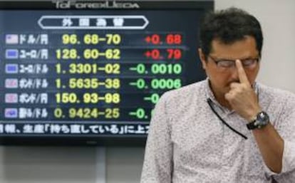 Un empleado de una oficina de corretaje se ajusta las gafas ante una pantalla con los tipos de cambio de moneda extranjera, en Tokio.