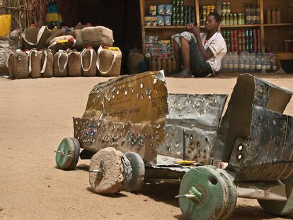 Estamos en Dirkou. Un niño se ha hecho este juguete a imitación de los camiones que cruzan el desierto cargados de seres humanos. Al fondo, una de las muchas tiendas de Dirkou que venden comida envasada para el viaje.