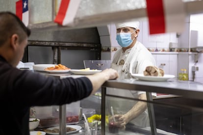 Un cocinero habla con uno de los meseros de El Hoyo mientras están en servicio, en Santiago.