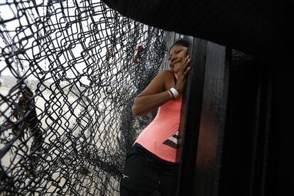 Una emigrante hondureña, seguida de su hija, trata de atravesar un hueco en el muro fronterizo que separa Tijuana (México) de EE UU.