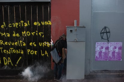 Un manifestante se refugia de los gases lacrimógenos lanzados por las fuerzas de seguridad.