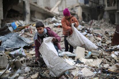 Niños sirios recogen maderas entre los escombros para calentar y cocinar, en la zona rebelde de la periferia de Damasco (Siria).