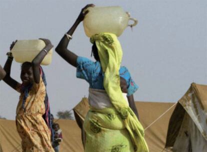 Varias mujeres africanas transportan agua en garrafas.