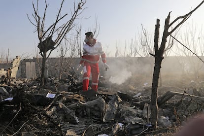 Agente de resgate caminha entre os restos do avião.