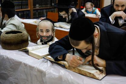 Judíos ultraortodoxos, incluido un niño disfrazado, estudian durante la fiesta de Purim en una sinagoga.
